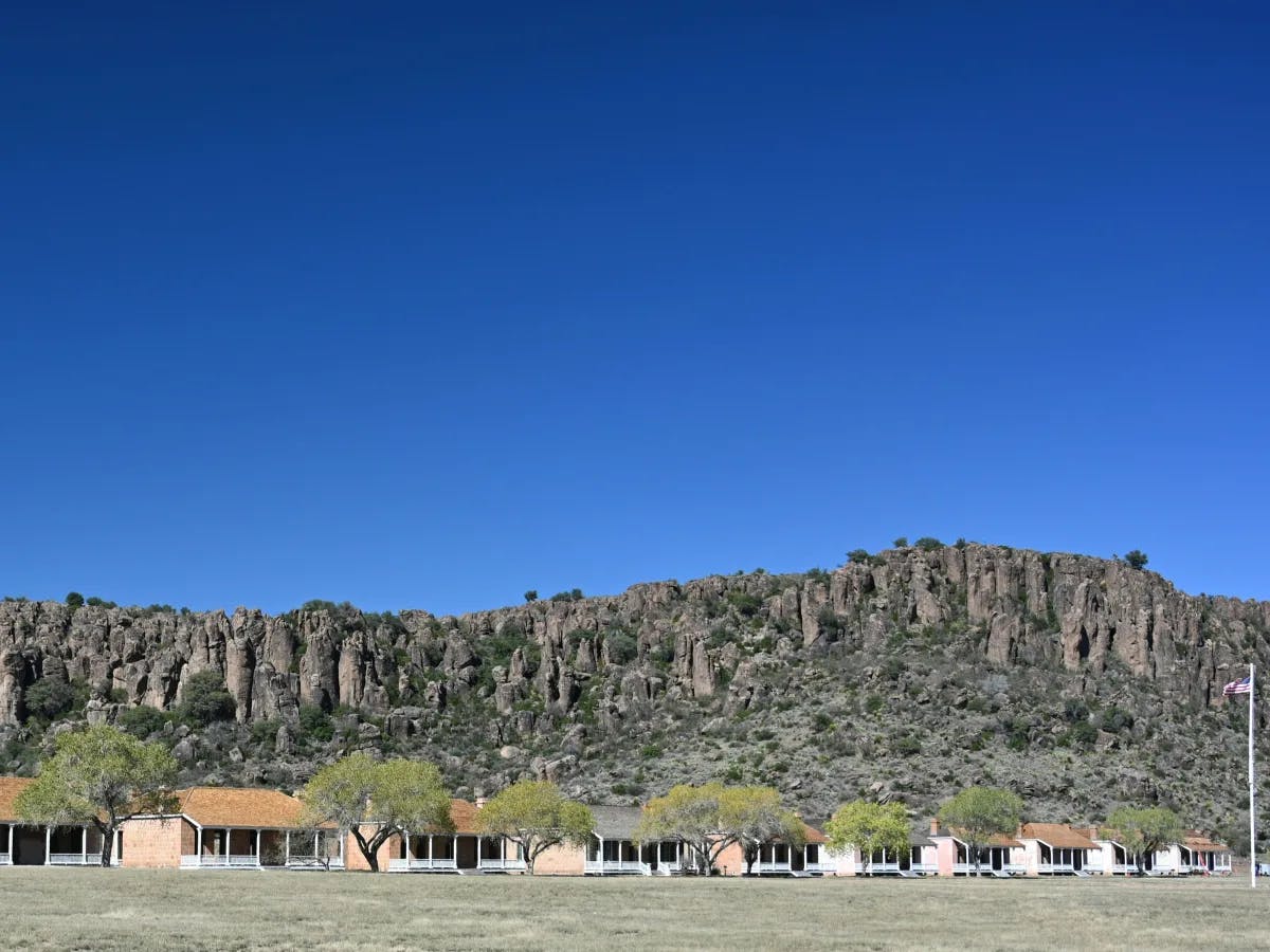 A row of houses in front of a mountain range under the blue sky.