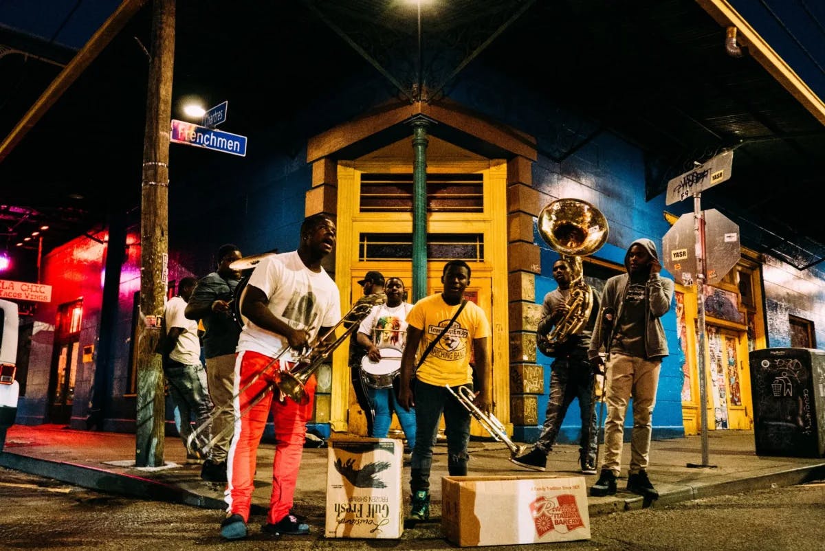 People holding musical instruments while standing on street at night. 