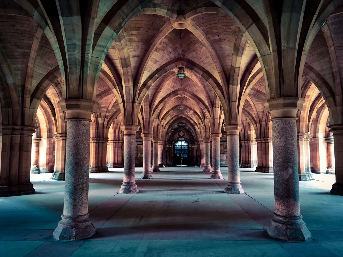 The cloisters at the University of Glasgow, with arches over a concrete walkway.