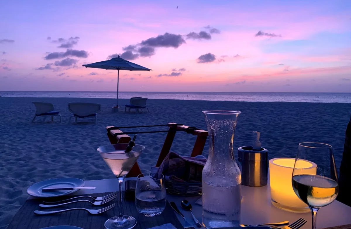 Dinner by the beach with a romantic sunset and the ocean in the distance.