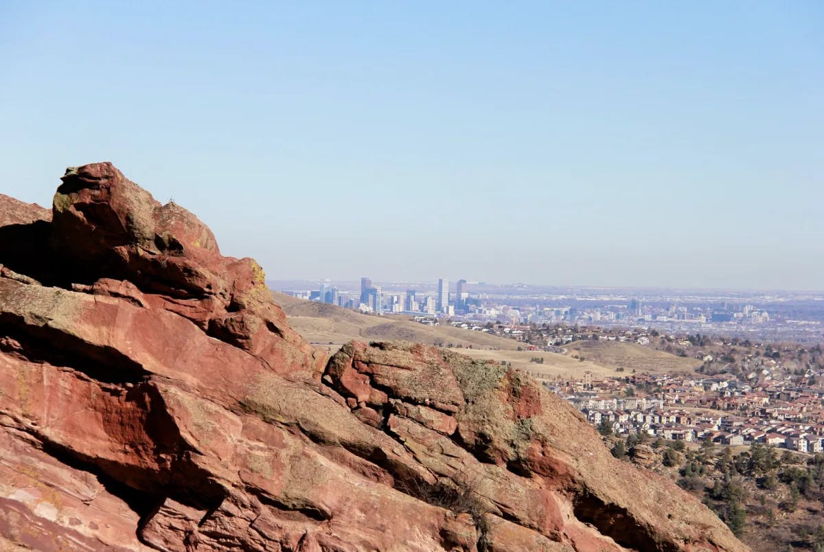 A large rock formation with a city skyline in the distance. 