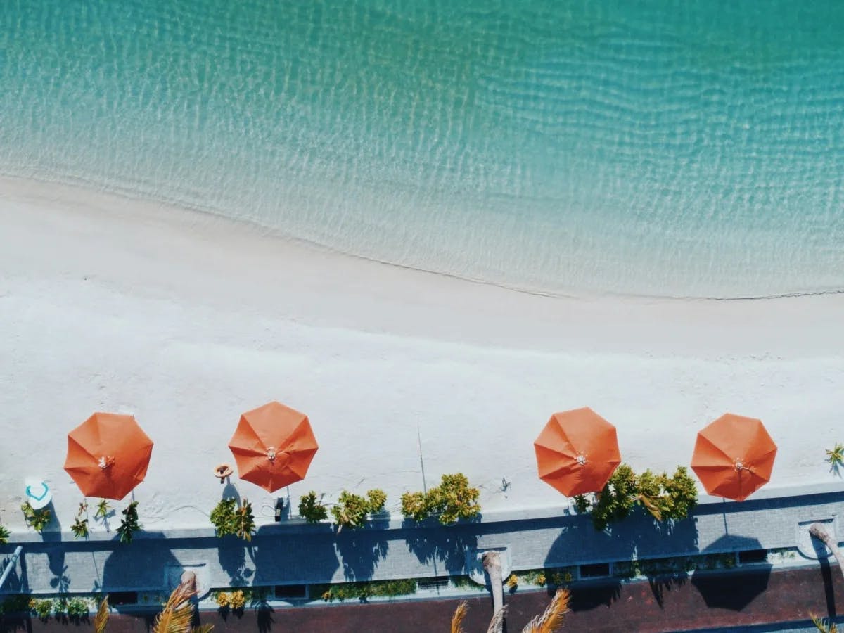 Aerial view of a beach restaurant with orange umbrellas.