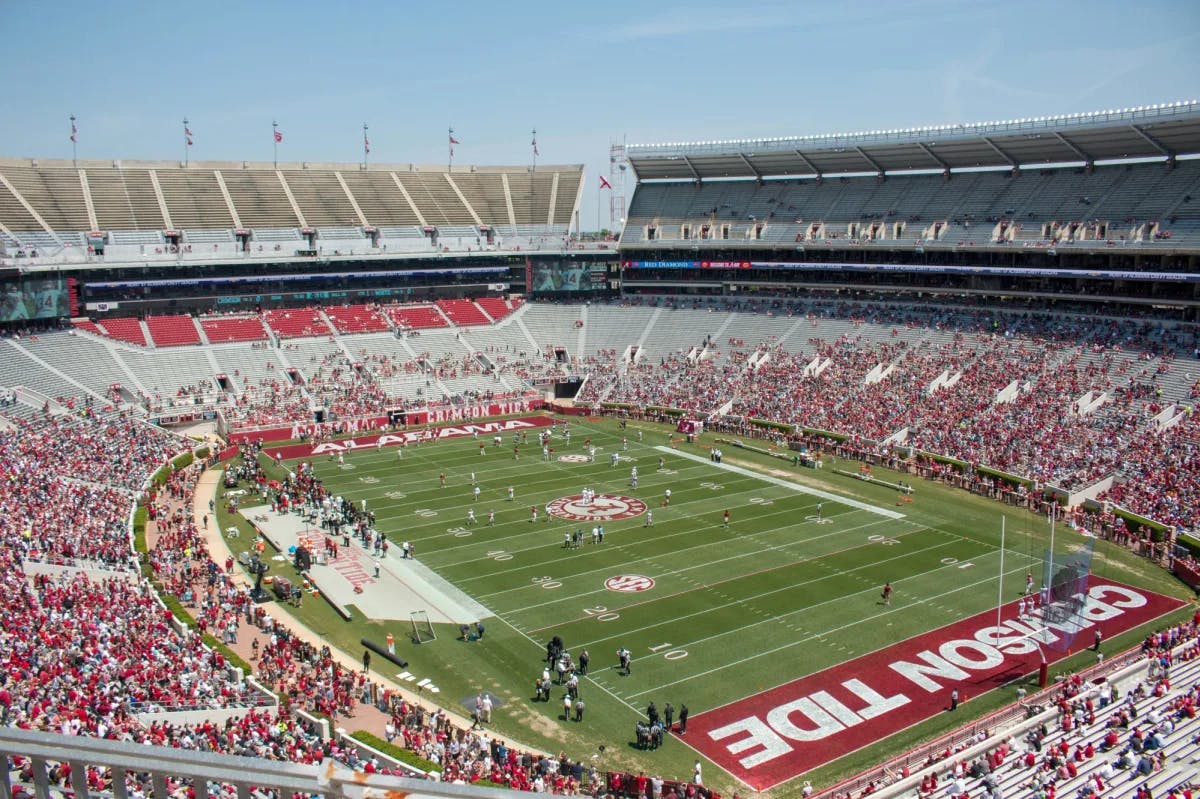 A football game in a stadium with "Crimson Tide" on the field.