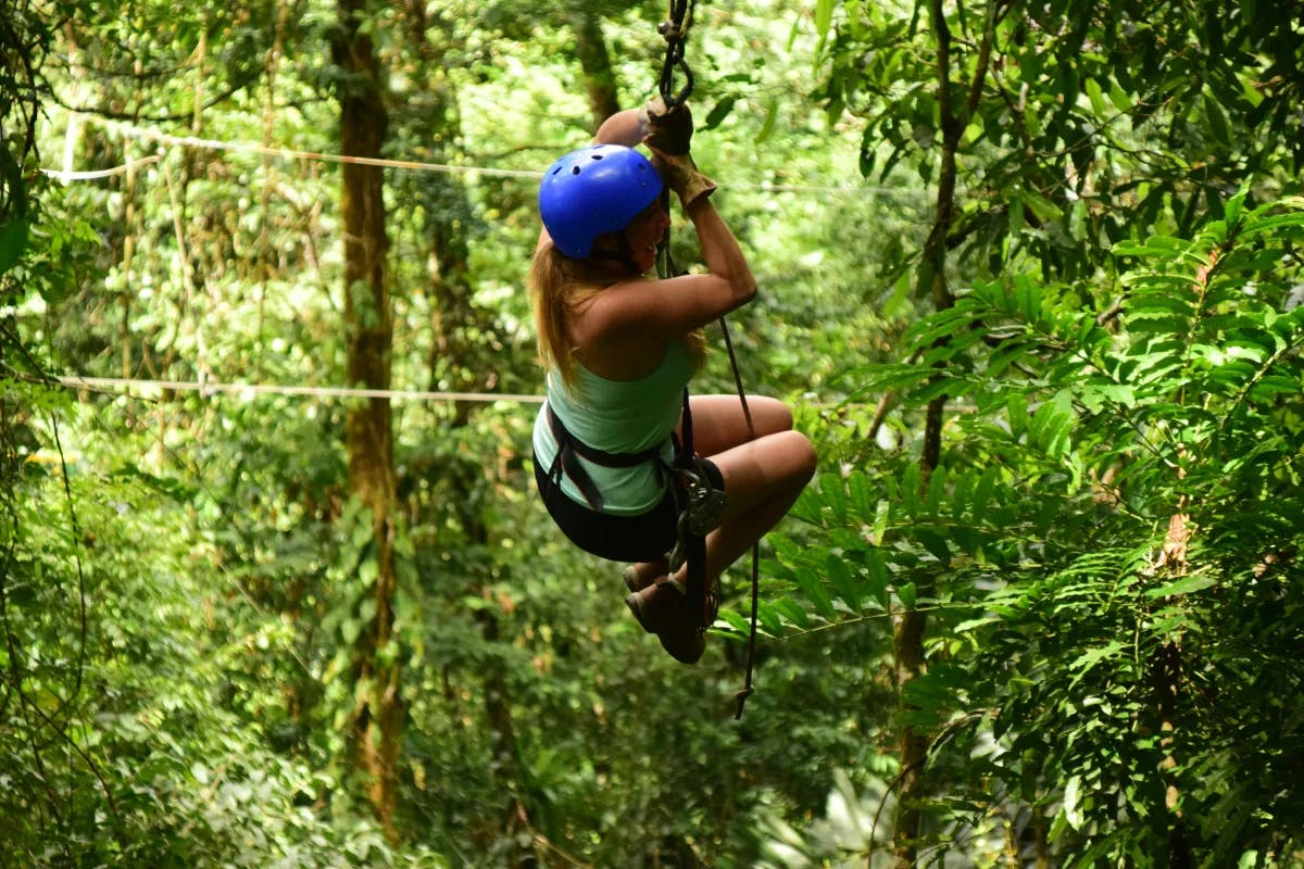 A woman on a zip line through trees in Maya Riviera Mexico.