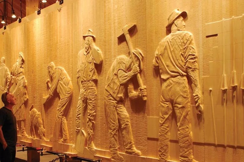 The Wall in the Wilderness, a wooden wall with carvings of men with shovels and tools.