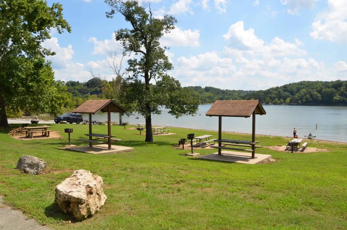 Table Rock Lake State Park, with grass and covered picnic tables next to the water.