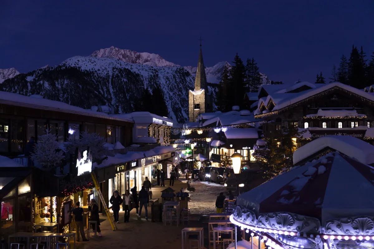 Courchevel at night with all the lights lit up with snowy mountains in the distance. 