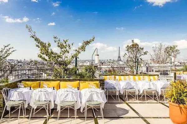 Perruche, a Mediterranean rooftop restaurant with yellow cushions and white tablecloths with view of Eiffel Tower.