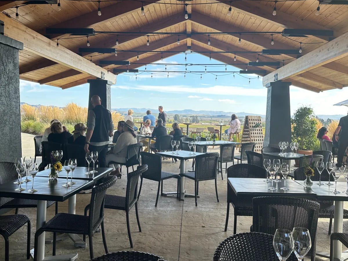 The Gloria Ferrer patio with tables under a large wooden awning overlooking the vineyard.