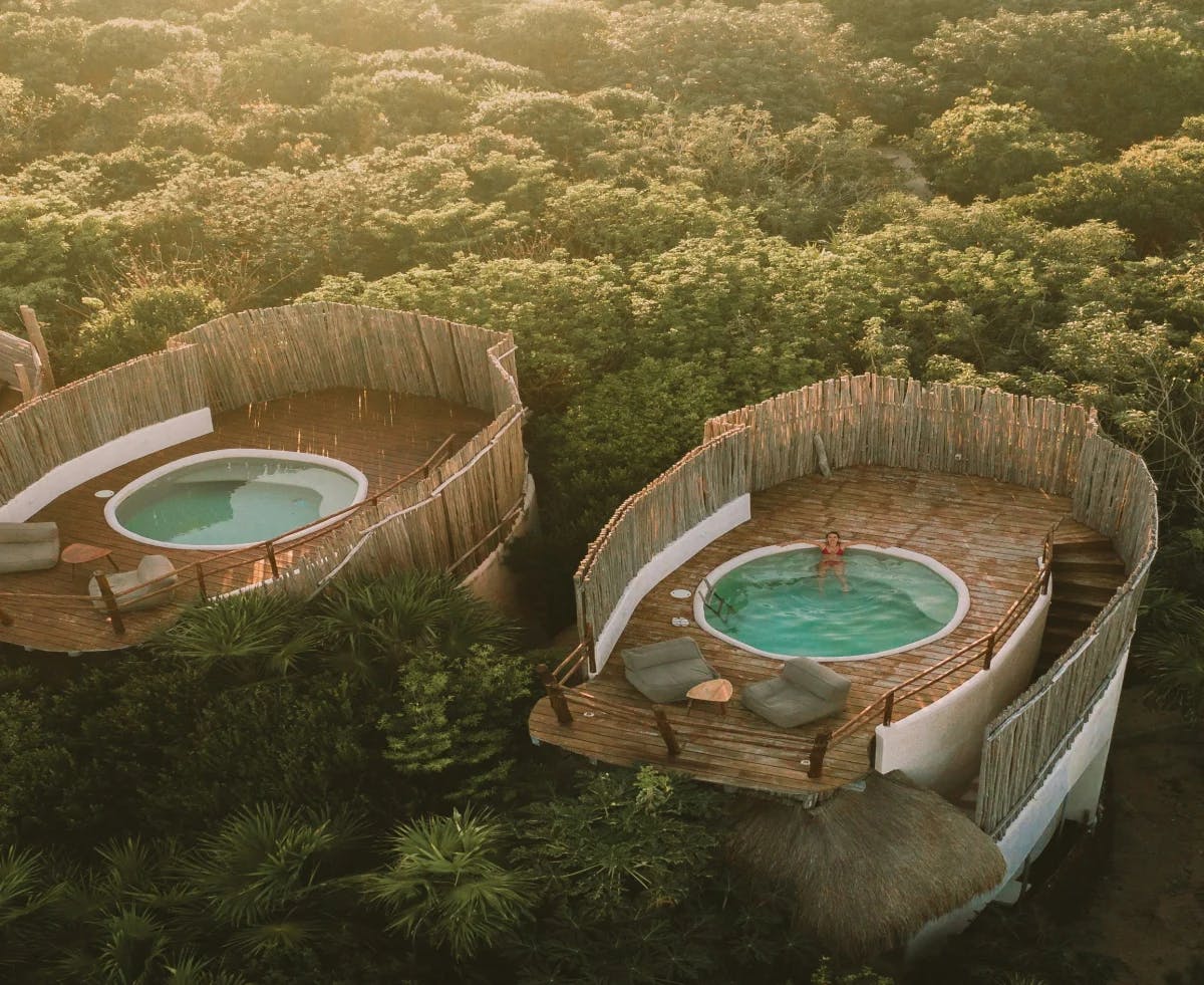 An aerial view of rooftop hot tubs in the middle of a green forest in Maya Riviera Mexico. 