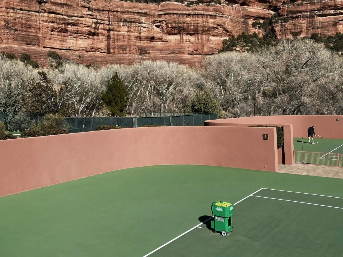 Green tennis court with red clay walls near red rocky mountains at one of the best resorts in Sedona AZ for couples.