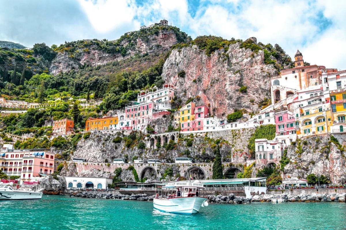 A turquoise blue body of water with a colorfully vibrant Italian coastal town in the background. 