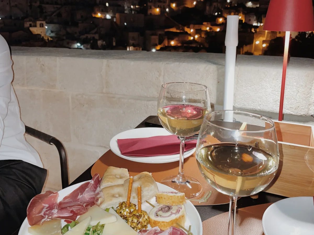 A plate of food on a table with glasses of white wine