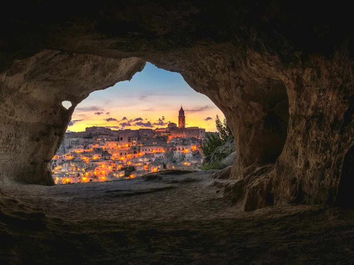 A picture taken from a cave of the city at sunset.