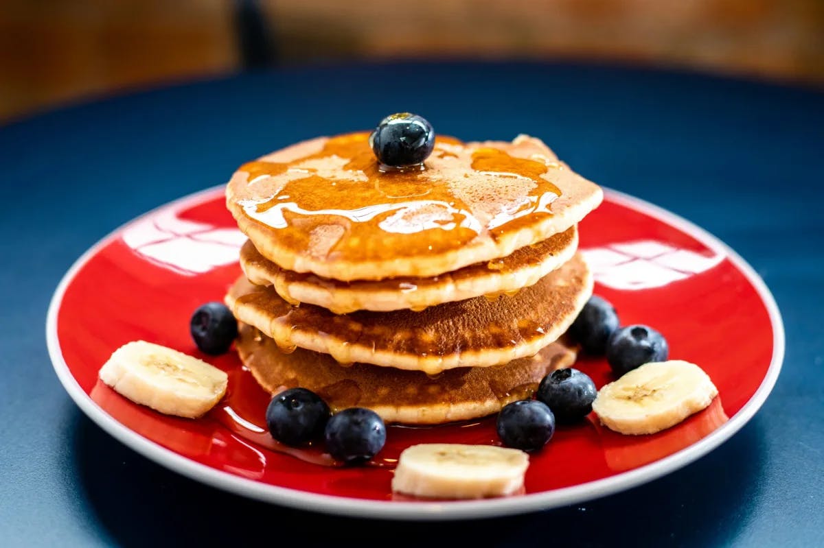 A stack of pancakes with banana and blueberries. 