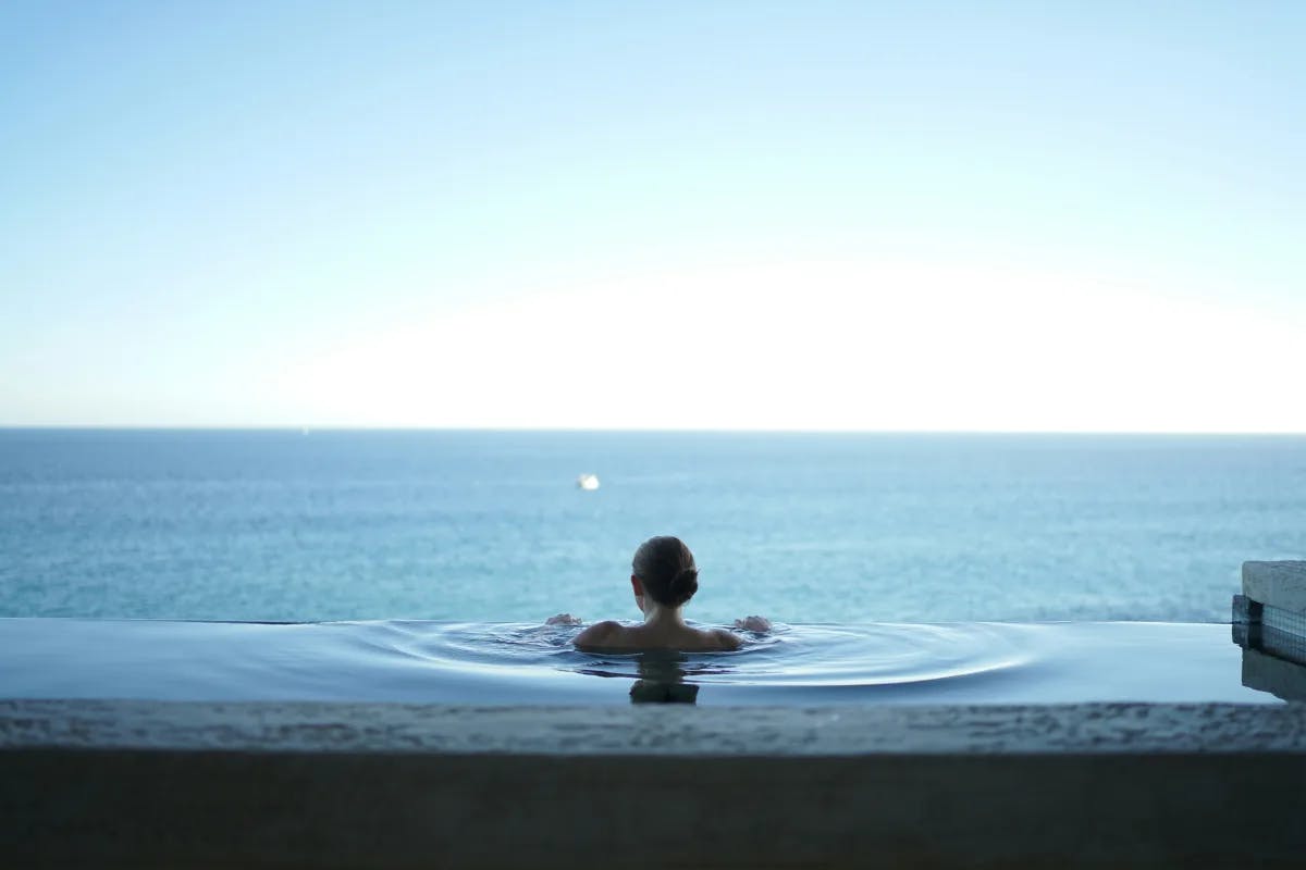 A picture of a woman in the pool looking at the lake.