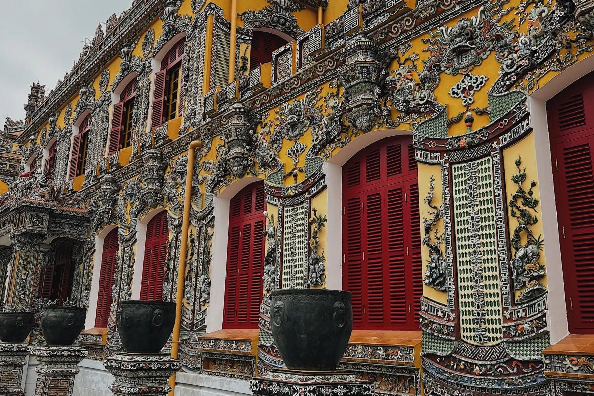 Kien Trung Palace with a very elaborate yellow and white facade with many figures and red doors