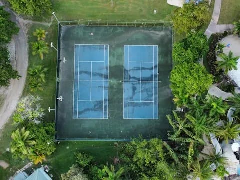 An aerial view of a tennis court in the middle of a green field