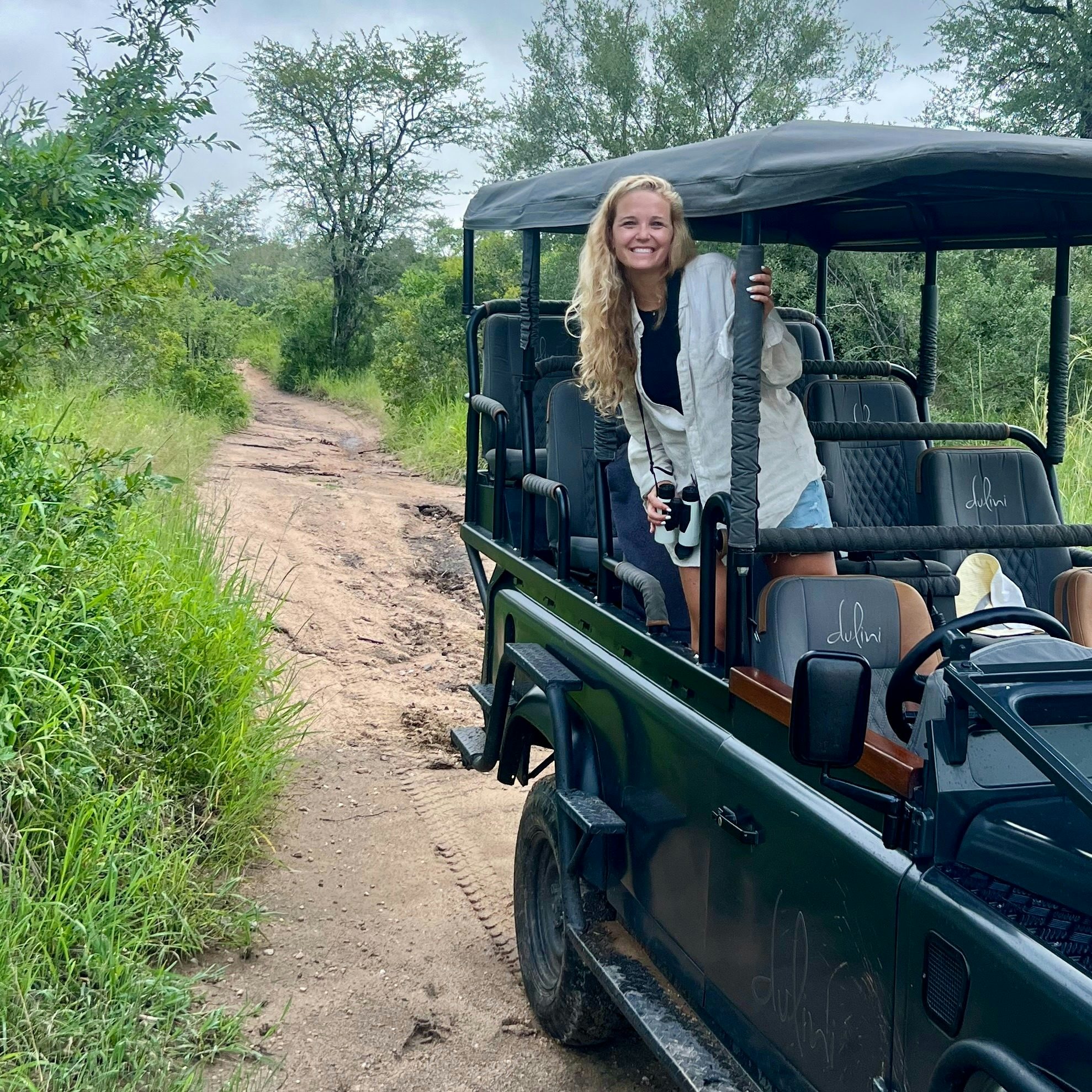 Travel advisor Jeannie Peters in a white top standing up in an open-air vehicle on a trail