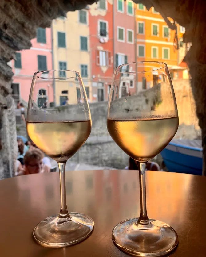 Picture of two glasses of wine on a table with colorful buildings behind