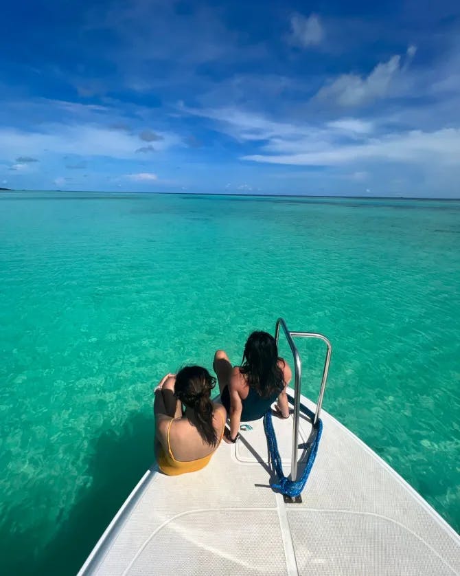 Travel advisor Sharon and female companion sitting on a boat looking out at turquoise ocean
