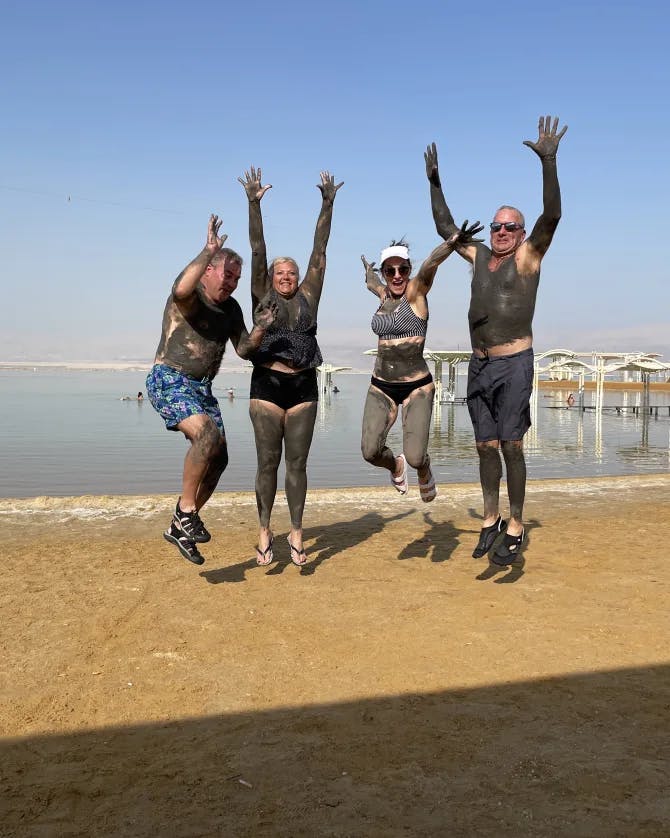 Travel advisor Leah Bedgood and three others jumping on a beach covered in mud