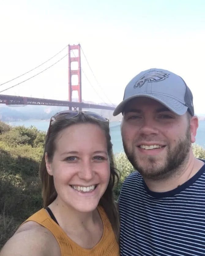 Elizabeth and a partner posing for a selfie outside in front of the Golden Gate Bridge. 