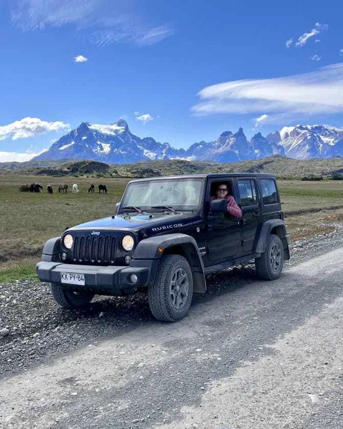 Travel advisor Paige in jeep with animals and snow-capped mountains in view