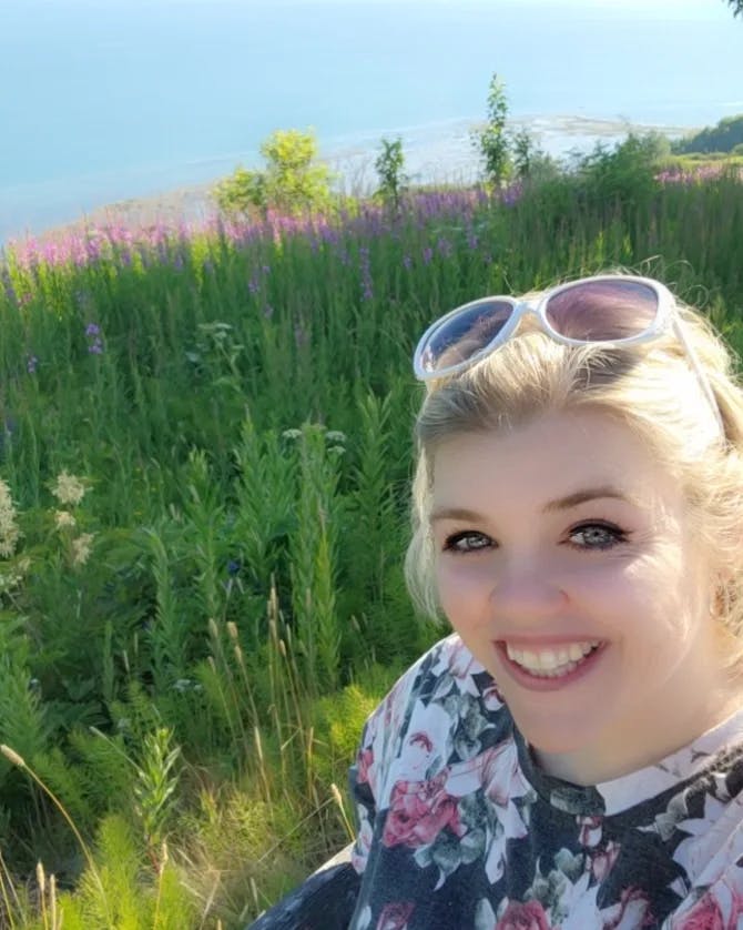 Travel advisor Erin posing for a selfie in front of beautiful view of purple flowers