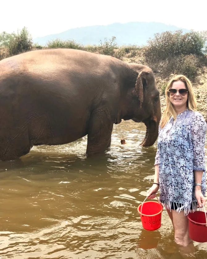 Ashley standing with elephants in an elephant sanctuary. 