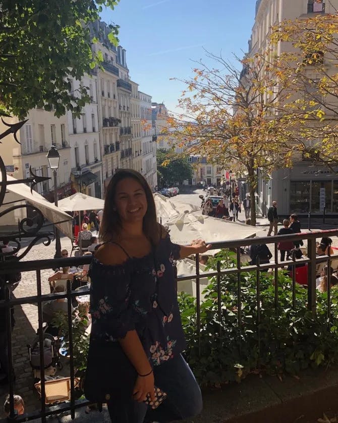 Travel advisor Vanessa standing against a railing overlooking a pretty street and outdoor restaurant