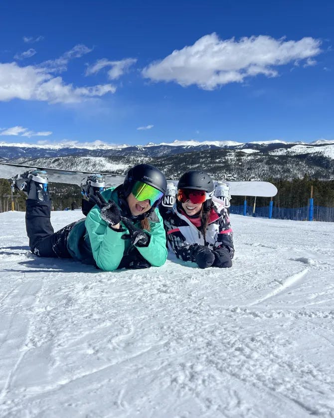 Travel advisor Sarah lying down in ski suit on ski slope with companion