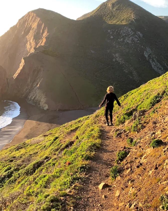 View of person walking on MillValley Beach Trail with ocean and mountain in view