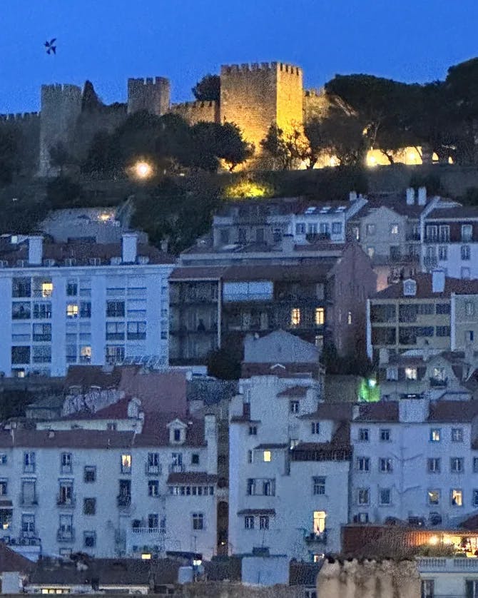 Night view of a city with buildings on a hillside and illuminated castle