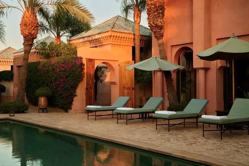 A few lounge chairs with umbrellas line a courtyard pool belonging to a top-tier unit at Amanjena in Marrakech