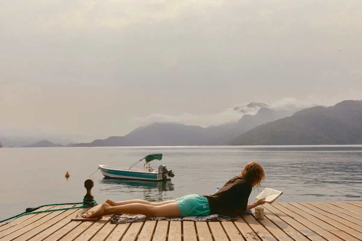 Women lying on dock next to lake