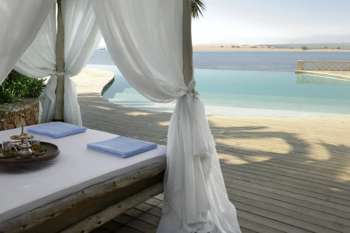 A private terrace with elaborate bed setting and patio leading to an infinity pool that looks out over the Oualidia lagoon