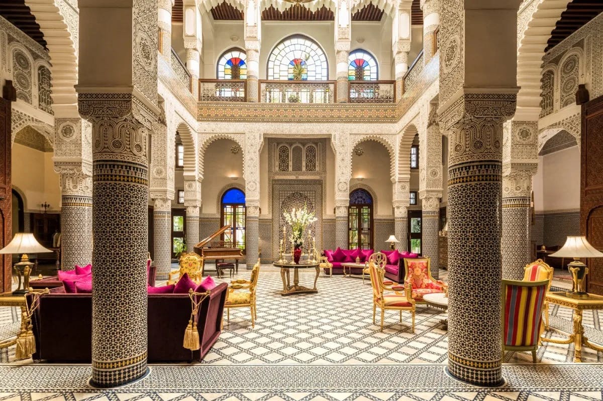 Tiled columns and archways surround an opulent courtyard filled with lavish decor and furnishings at Riad Fes, one of the top hotels in Morocco