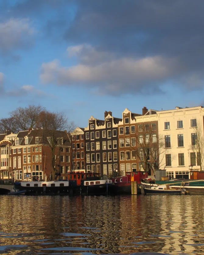 A view of the Amsterdam canal with boats docked and a line of buildings 