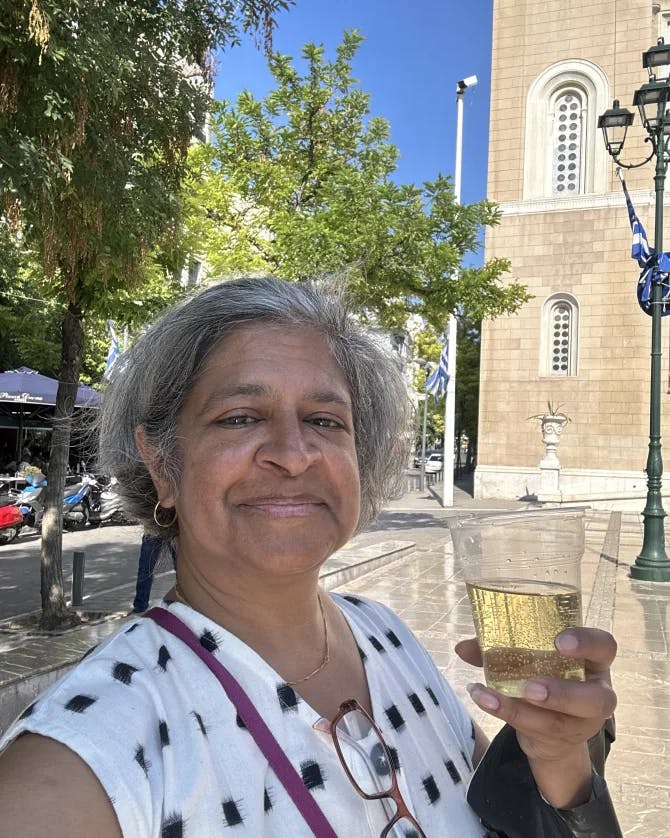 Travel advisor Swati in a white top in the street with a drink in hand