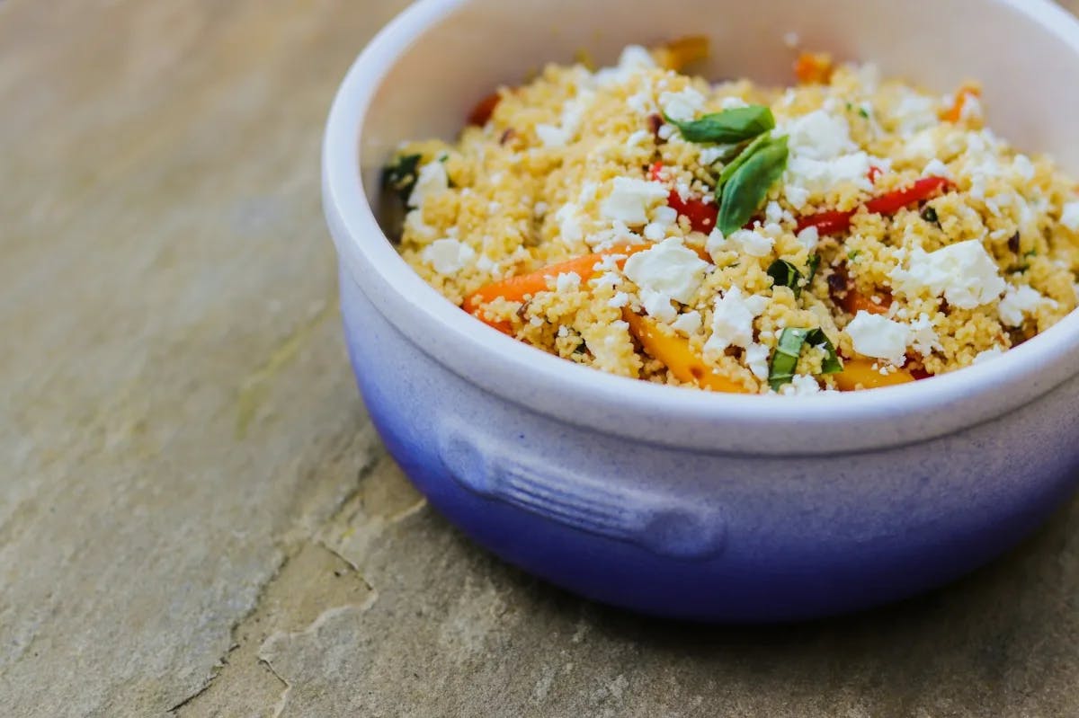 A colorful couscous dish served in a traditional clay bowl
