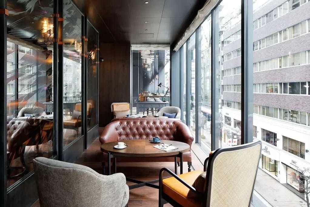 a balcony with leather couches and plush chairs above an urban street