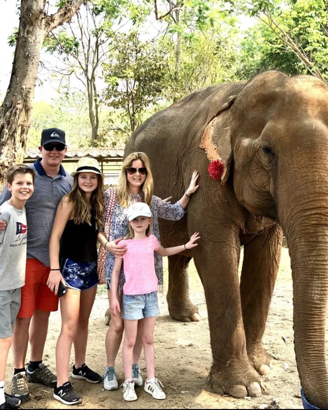 Ashley and her family standing with an elephant in an elephant sanctuary. 
