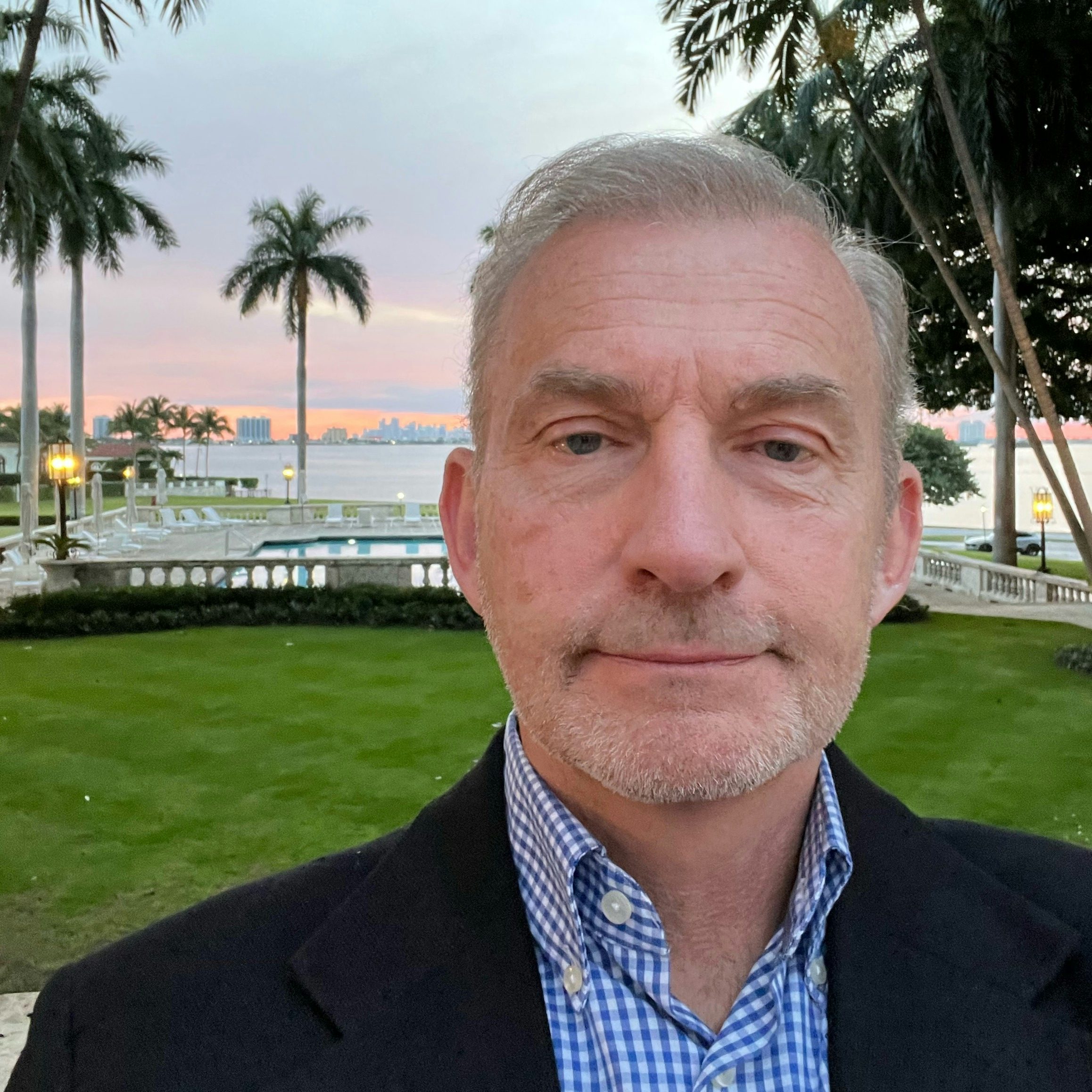 Travel Advisor David Pierce in a suit in front of palm trees at sunset.