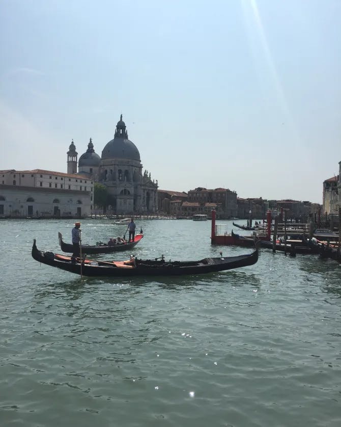 View of boats on Venice canal with dome-shaped building in the background
