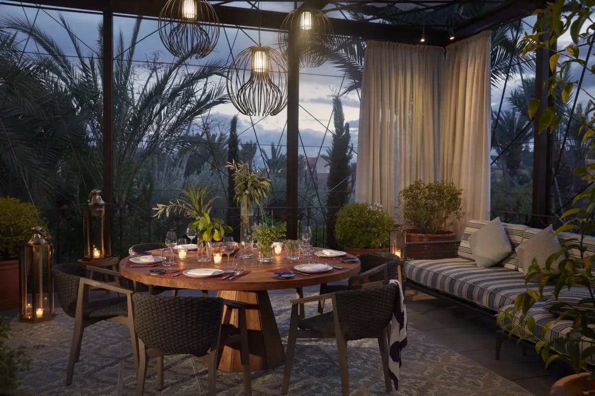 A private, group dining setup within a glass room surrounded by plants and gardens at Royal Mansour Marrakech