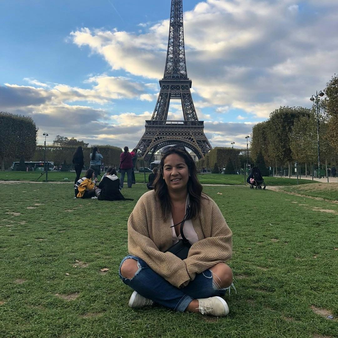 Vanessa Callahan sitting on the grass with Eiffel Tower in view