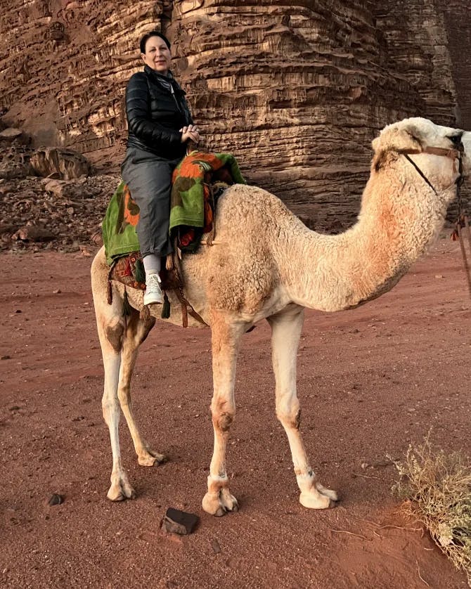 Travel advisor Suzanne riding camel on red-colored landscape