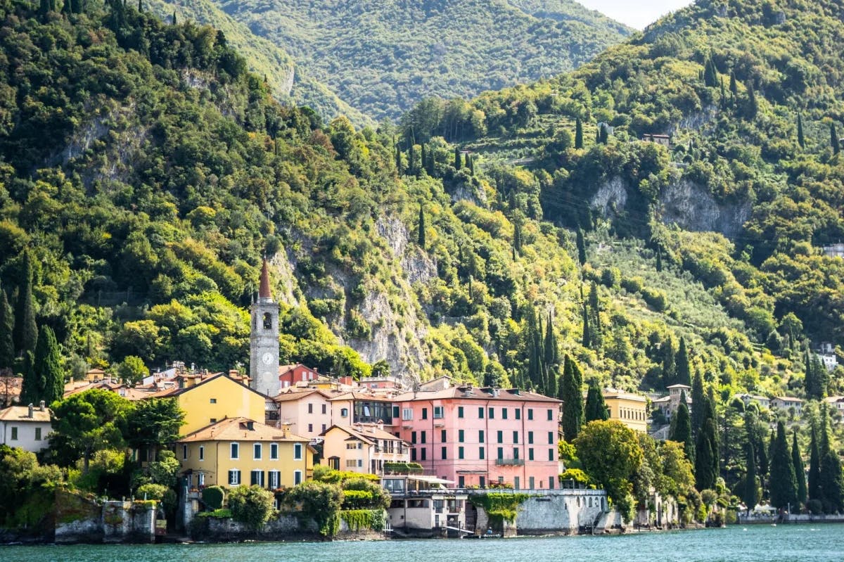 Beneath lush hills, colorful historic buildings line the shores of Lake Como, Italy