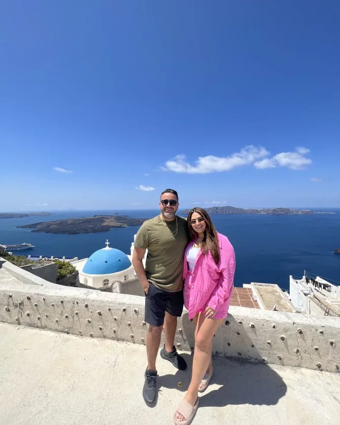 Travel advisor Riva Hanna posing for a picture with male companion in front of the ocean in Santorini